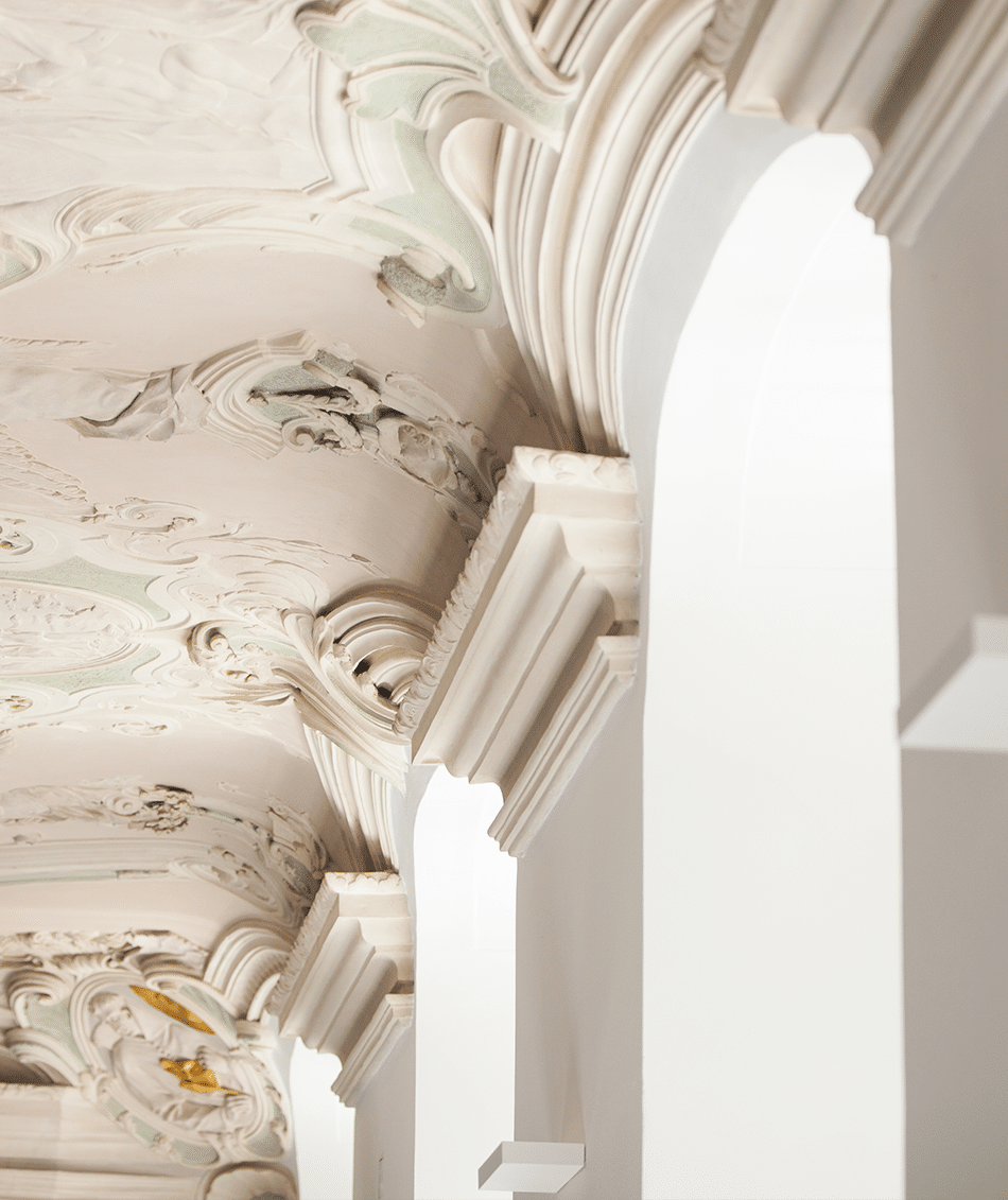 Blick an die Stuckdecke und Fensterlaibungen eines historischen Gebäudes.