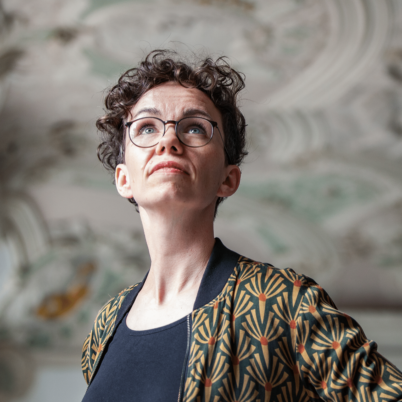 Verena Smit betrachtet die Stuckdecke eines historischen Gebäudes.