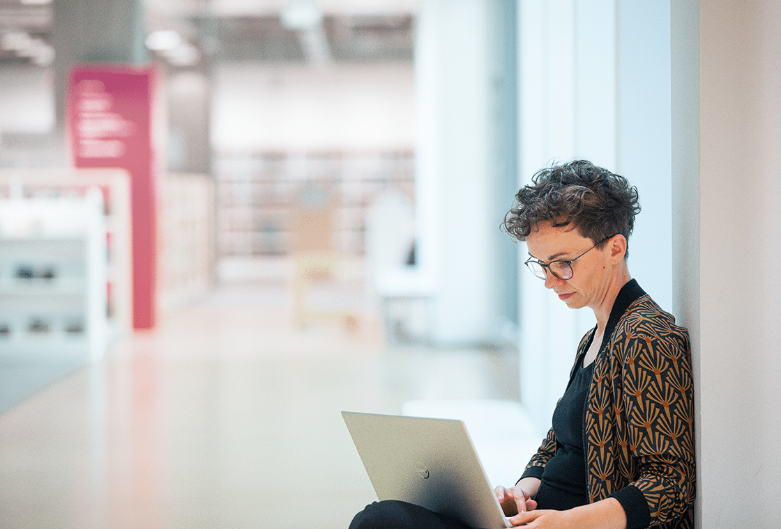 Verena Smit nimmt mit dem Laptop auf dem Schoß von unterwegs online an einer Redaktionskonferenz teil.